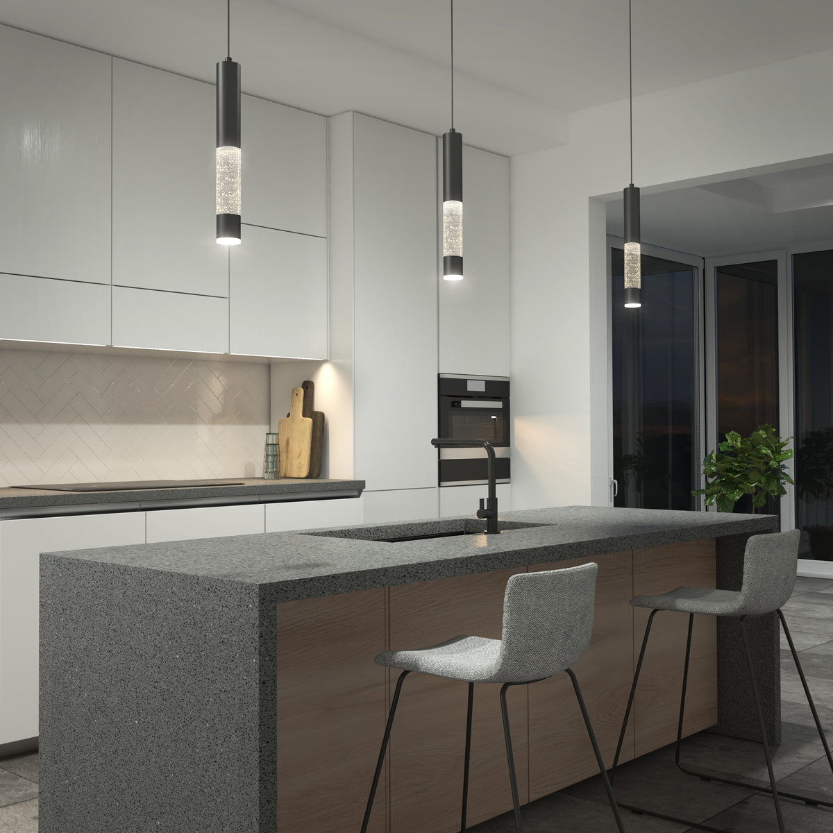 Modern kitchen with a gray stone island, two cushioned barstools, sleek pendant lights, built-in cabinets, a cutting board, and a potted plant near large windows at night.
