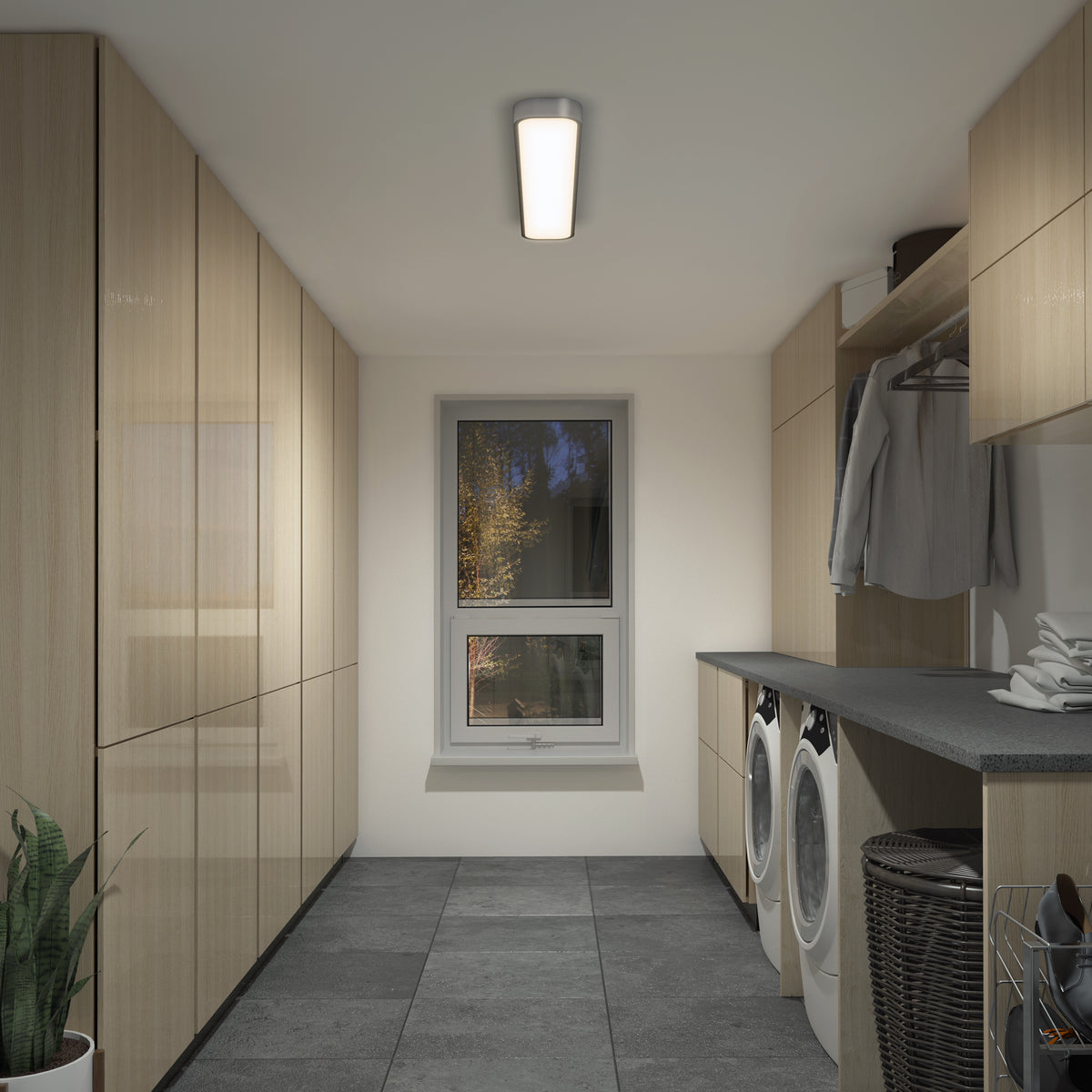 Modern laundry room with light wood cabinets, gray countertops, washer and dryer, window with a view of trees, hanging clothes, baskets, potted plant on tiled floor, and an Artika Europa 36 LED flush mount light with remote.