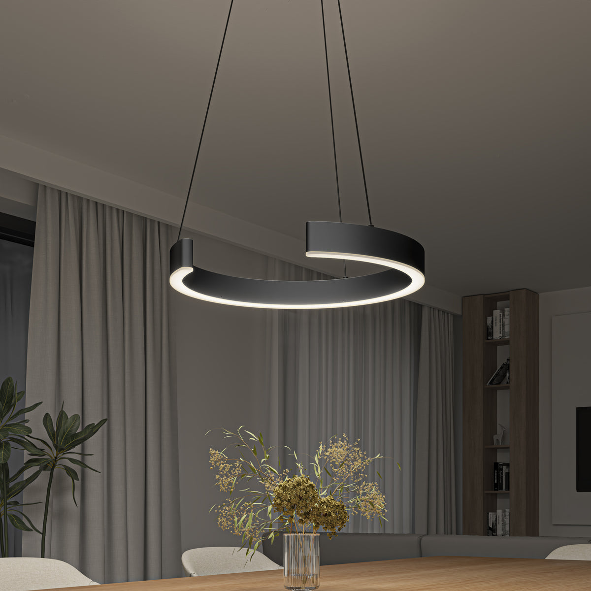 An Artika Vance modern LED pendant light (3 CCT) hangs over a wooden dining table with a glass vase of dried flowers. The room features beige curtains, a large window, and built-in shelves in the background.