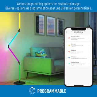 A modern living room features the Artika Fitch smart foldable RGB LED gaming floor lamp next to a sofa. A smartphone displays smart customization options. Text above reads, “Various programming options for customized usage.”.