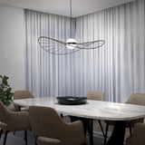 A modern dining room with a marble table, beige upholstered chairs, a black centerpiece bowl, and a unique sculptural pendant light, set against white curtains and a plant in the corner.