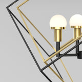Close-up of a modern geometric chandelier featuring black and gold metal frames with two spherical frosted bulbs on gold cylindrical bases against a plain light background.