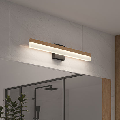 The Artika Neil modern LED bathroom vanity light with a wooden accent and frosted panel is mounted above a bathroom mirror, lighting up the tiled wall. Below, a glass shower enclosure and green plant can also be seen.