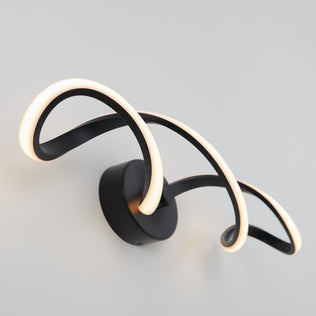 The Artika Swirl LED bathroom vanity light features two curved black metal arms with integrated LED strips, forming a modern, abstract design that enhances any light-colored wall.