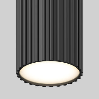 A close-up of the Artika Groove LED modern pendant light 3 CCT, featuring a ribbed dark gray cylindrical exterior and a glowing matte white bottom, set against a plain gray background.