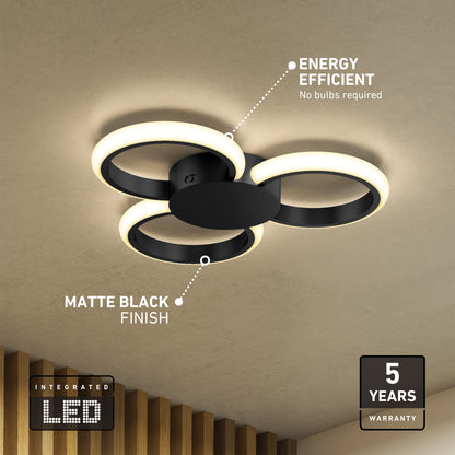 The Artika Nyala 15 in. LED flush mount light 5CCT features three interconnected LED rings, a matte black finish, energy efficiency, integrated LEDs, and a 5-year warranty. Shown mounted on a beige ceiling.