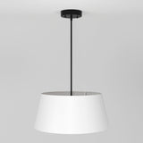 A modern ceiling pendant light with a black rod and a wide, white lampshade hanging from a white ceiling against a plain gray background.