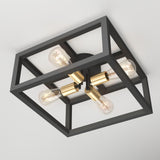 A modern ceiling light fixture with a black geometric metal frame, four exposed bulbs, and gold central accents, mounted flush against a white ceiling.