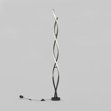 A modern floor lamp with two twisting, intertwined black and white LED light strips, standing on a round base with a power cord and switch on a plain light gray background.