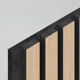 Close-up of a modern wall panel featuring alternating vertical strips of light wood and black material, viewed from an angle against a plain light gray background.