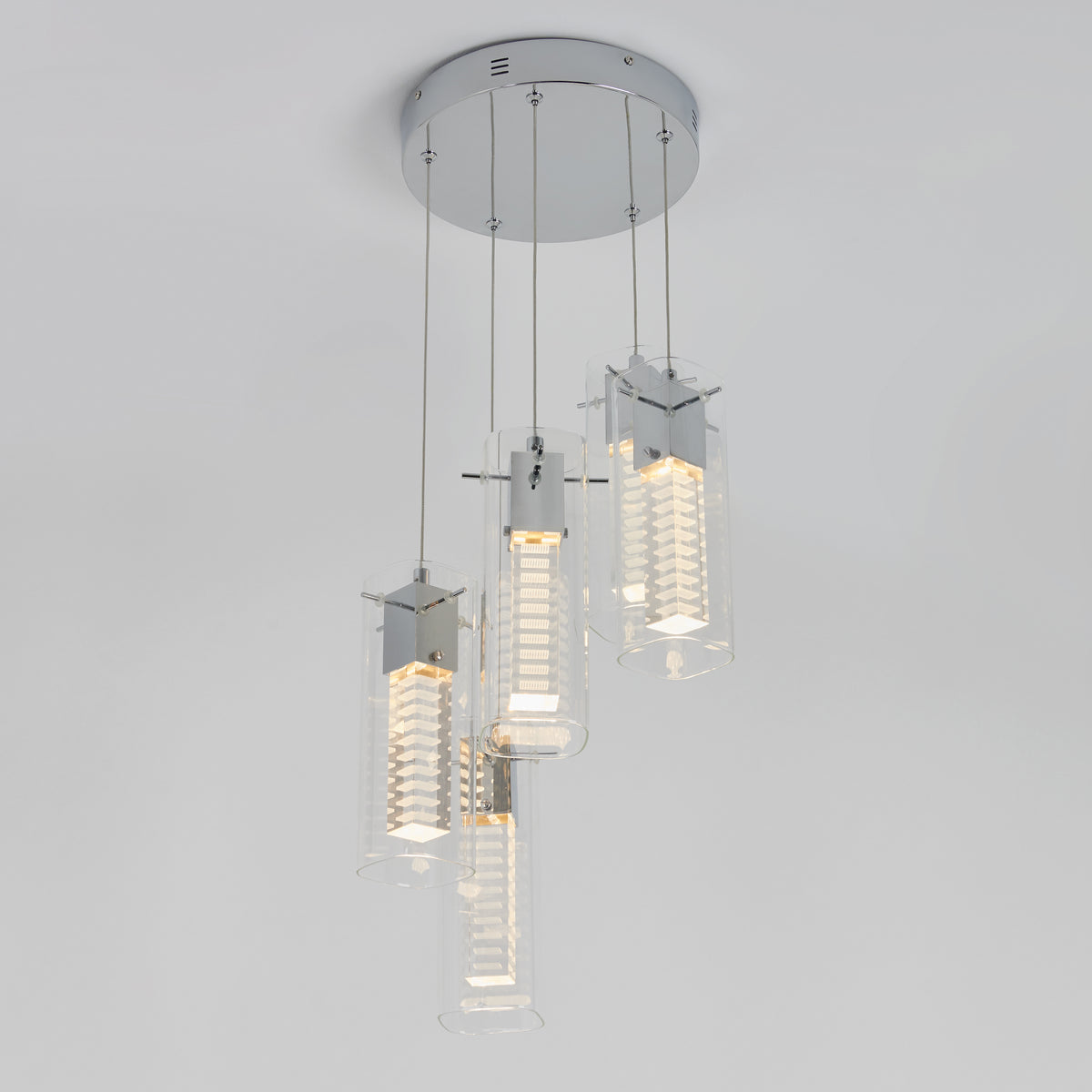 The Artika Hologram 5-light LED pendant features five cylindrical transparent glass shades with metallic accents, each suspended from a round chrome ceiling mount for a modern look.