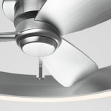 Close-up view of a modern ceiling fan with metallic, brushed silver blades and a circular light fixture attached to the base, set against a neutral background.