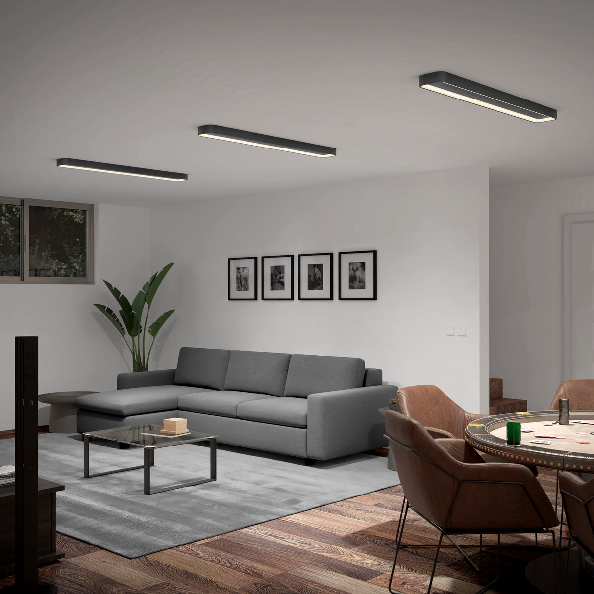 A modern living room with a gray sofa, a glass coffee table, wall art, a large plant, and stylish ceiling lights. A dining table with brown chairs is visible on a wooden floor with a gray rug.