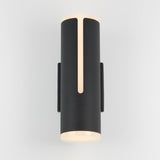 A modern black cylindrical wall sconce with soft white light glowing from the top and bottom, featuring a vertical light strip on the front, mounted on a light-colored wall.