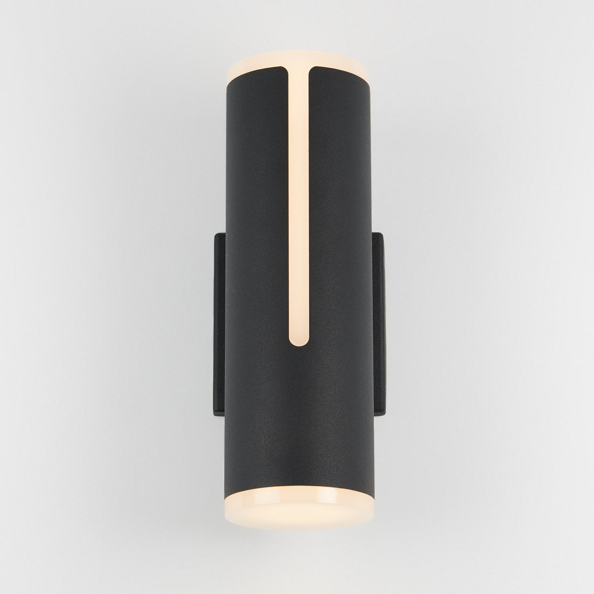 The Artika Linea modern indoor-outdoor LED wall light is a sleek black cylinder with soft, warm top and bottom glows and a thin vertical front light strip, shown mounted on a plain white background.