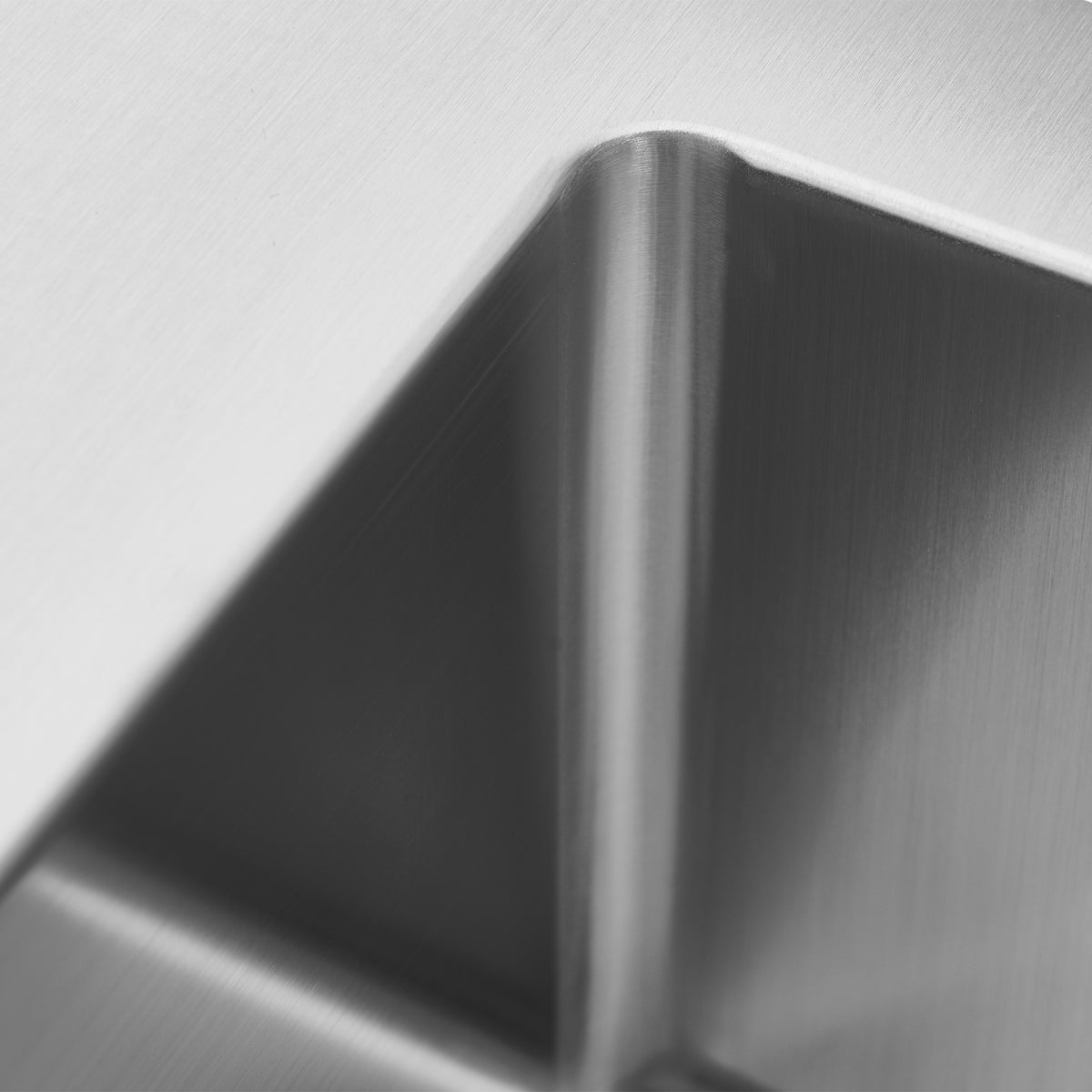 Close-up of a brushed metal surface with sharp, angular edges and smooth texture, creating geometric patterns and soft reflections.