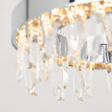 Close-up of a modern chandelier with a chrome finish, featuring hanging crystal prisms and warm glowing lights, creating a sparkling and elegant effect.