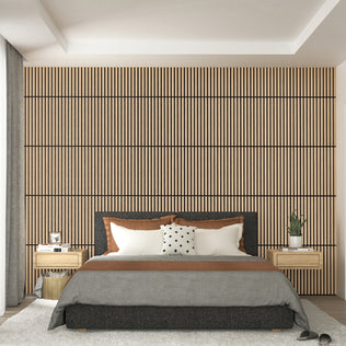 A modern bedroom featuring Artikas Sonolok 15.5 ft sound-absorbing wall panel kit as a wooden slat accent wall, a bed with gray and brown bedding, two nightstands with plants and lamps, and light curtains on the left.
