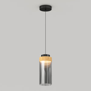 The Artika Hanson 1-light LED pendant 5 CCT features a black ceiling mount, black cord, cylindrical glass shade with a wooden accent on top, and emits a soft glow when illuminated.