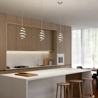 A modern kitchen features light wood cabinets, a marble island with three wooden stools, built-in appliances, sheer curtains for natural light, and Artika's Chorus 1-light LED pendant 5 CCT for stylish illumination.