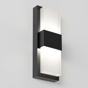 The Artika Mazza Frosted indoor-outdoor LED wall light features a sleek rectangular black metal frame with two frosted glass panels, casting a soft glow on a light gray wall.