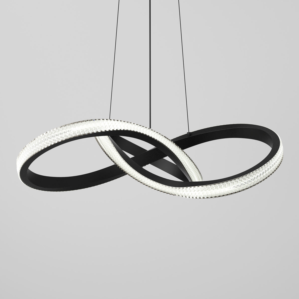 A modern pendant light with two large, interlocking black rings, one lined with bright LED lights, suspended by thin black cables against a plain light gray background.