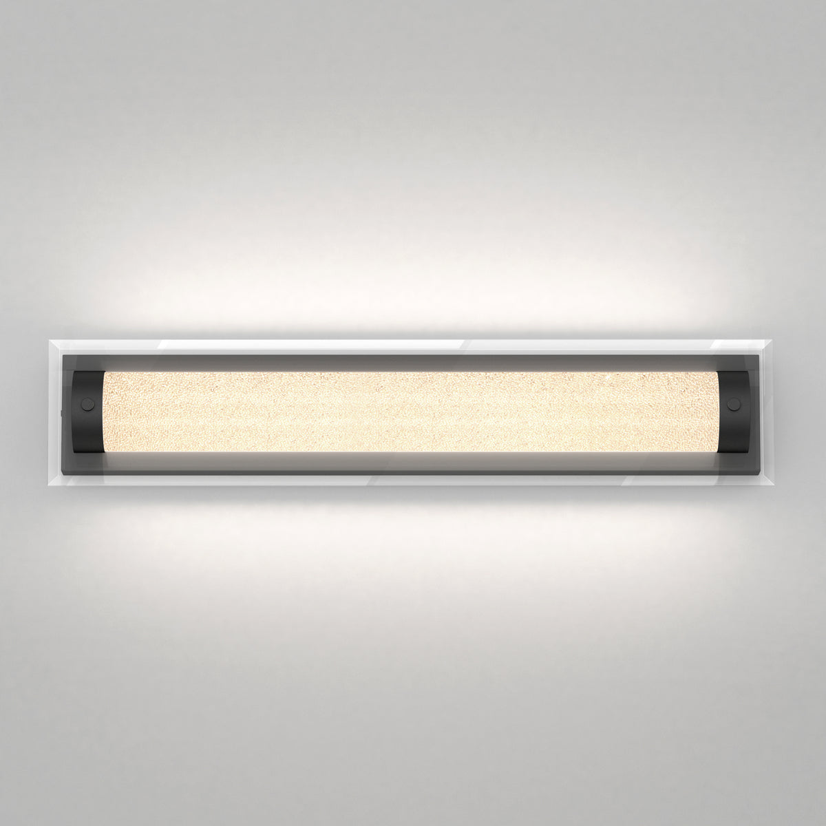A modern rectangular wall light fixture with a frosted glass cover and black end caps, mounted on a light gray wall and emitting a warm, even glow.