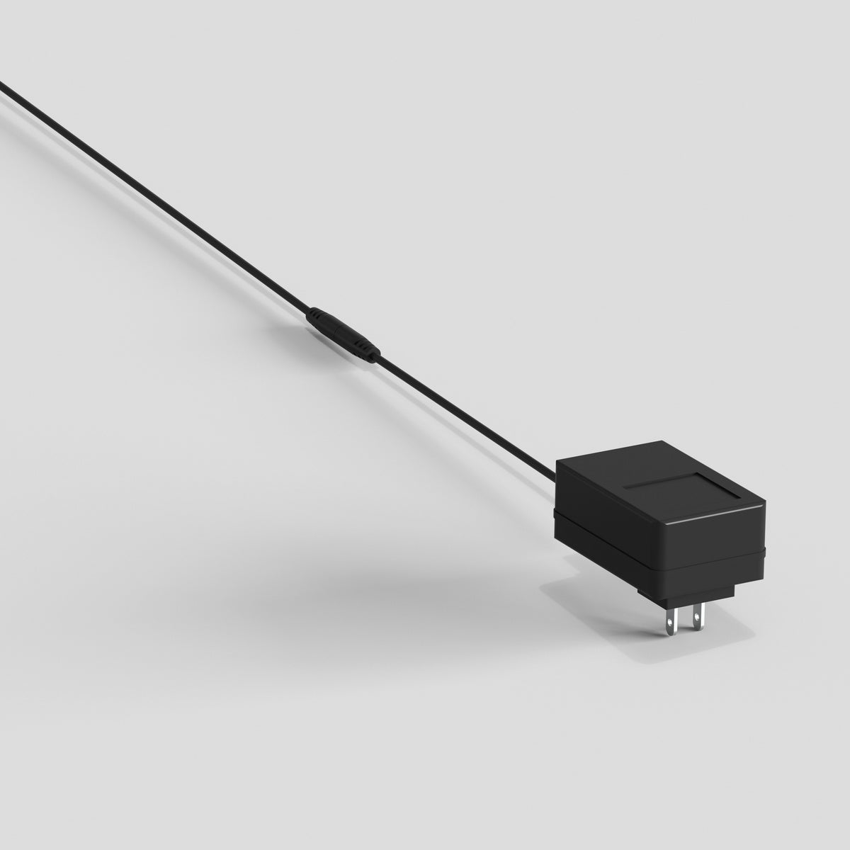 A black wall charger with an attached cable and inline control is placed on a plain white surface.