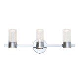 A modern three-light wall sconce with cylindrical glass shades featuring bubble-like details, mounted on a sleek chrome-finished horizontal bar and round base.