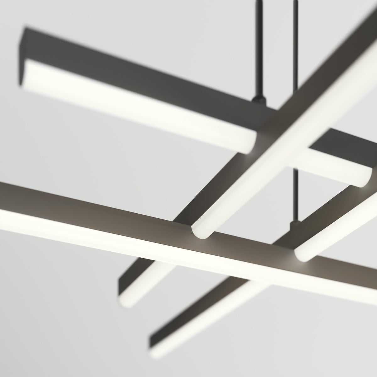 Close-up view of a modern, geometric ceiling light fixture with four elongated, glowing horizontal bars intersecting in a grid pattern against a plain, neutral background.