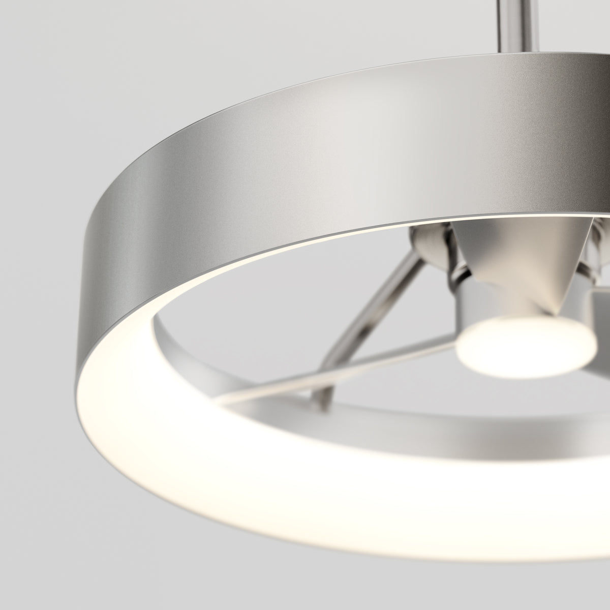 Close-up of a modern, circular metallic ceiling light fixture with a frosted ring emitting a soft, even white glow, set against a neutral background.