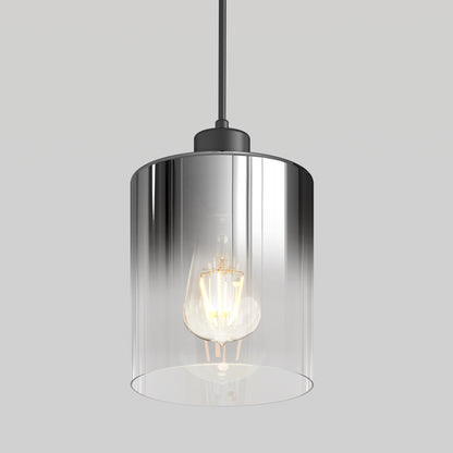 The Artika Haze pendant light features a clear cylindrical glass shade that reveals an exposed bulb, suspended by a black cord against a plain light gray background.