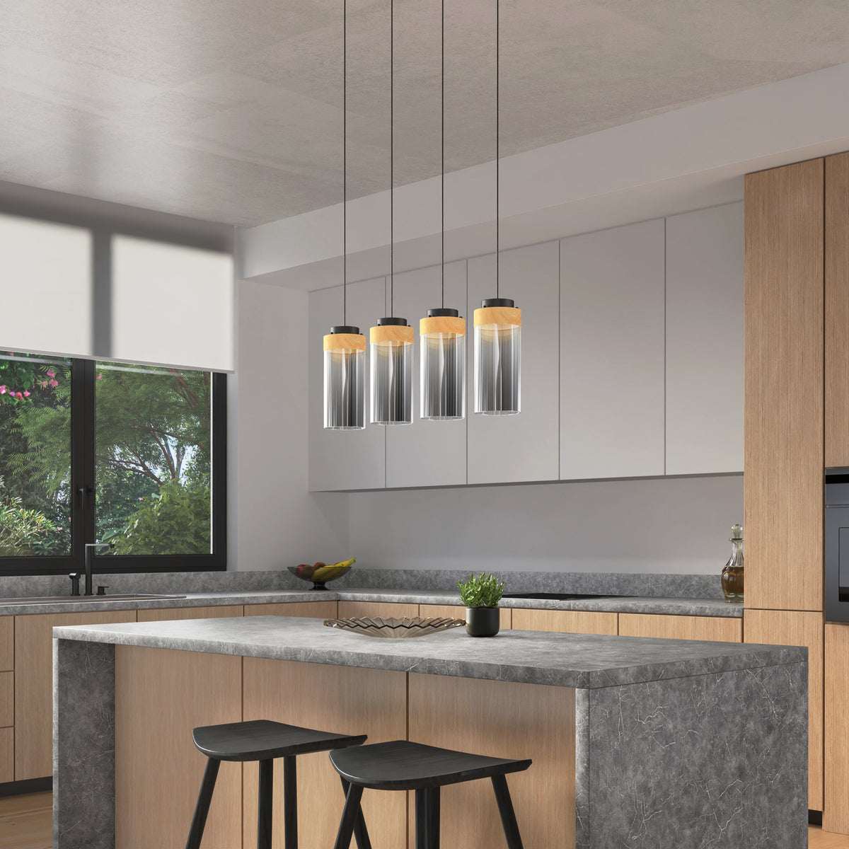 Modern kitchen with light wood cabinets, gray countertops, a large island with two black stools, pendant lights above, a potted plant on the island, and a large window with greenery visible outside.
