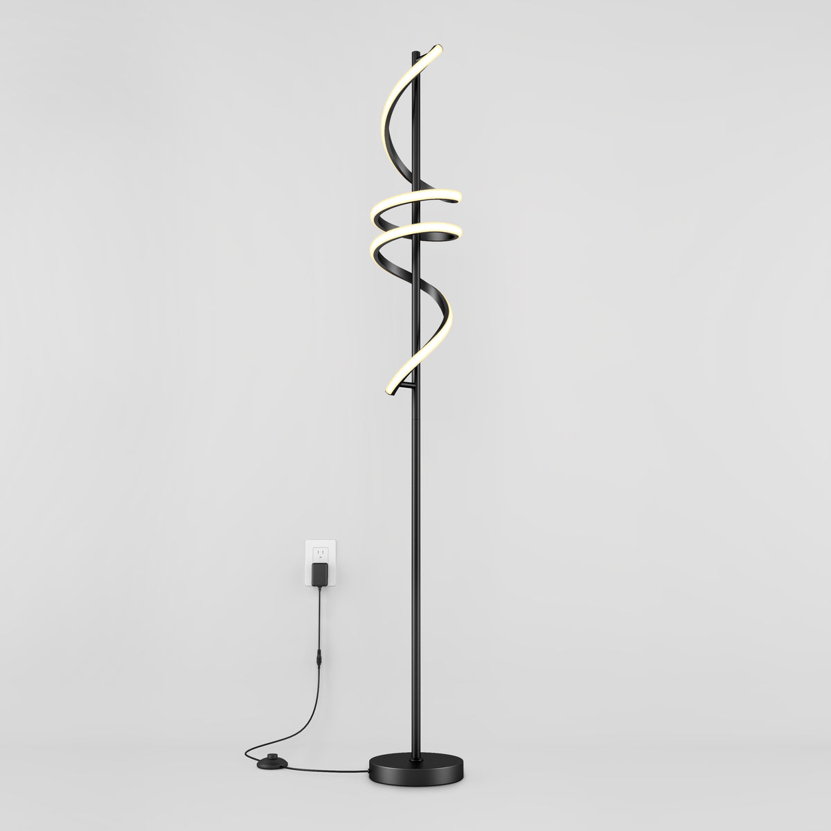 The Artika Coda modern LED floor lamp 5CCT features a black stand with three spiral LED light tubes, dimmable for customizable ambiance, standing against a white wall and plugged into a wall outlet.
