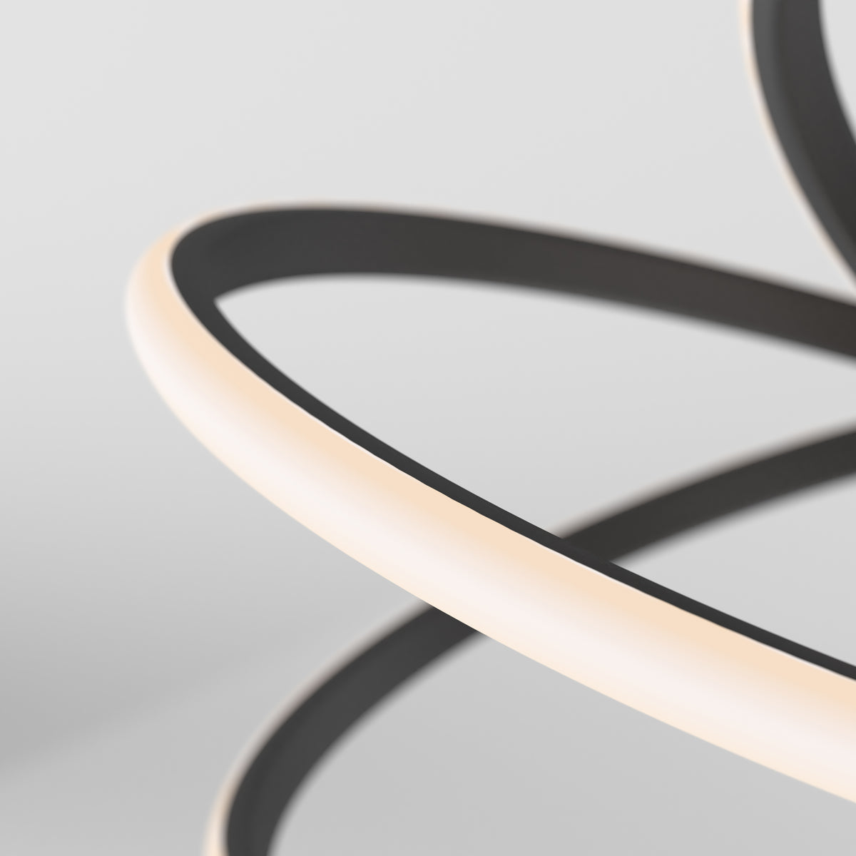 A close-up of a modern, abstract light fixture with curved, overlapping black and white LED strips set against a plain, light gray background.