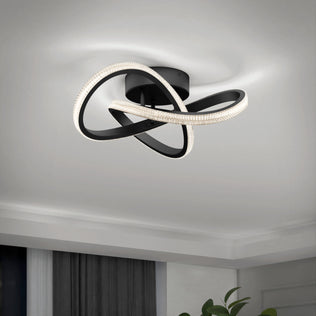 The Artika Morgan modern LED flush mount light 5 CCT features intertwined black bands and integrated LEDs, mounted on a white ceiling in a contemporary room with partial curtains and a plant in view.