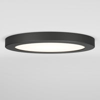 The Artika Europa Disk 7 in. LED modern flush mount light features a flat, round black design and offers 3 CCT options, emitting bright white light against a plain white ceiling and wall.
