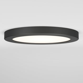 The Artika Europa Disk 7 in. LED modern flush mount light features a flat, round black design and offers 3 CCT options, emitting bright white light against a plain white ceiling and wall.