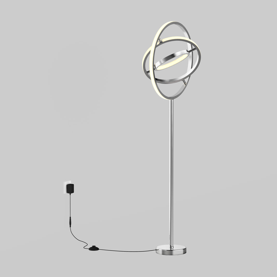 A modern floor lamp with circular, intersecting LED rings on a tall metal stand, plugged into a wall outlet with a visible power cord against a plain gray background.