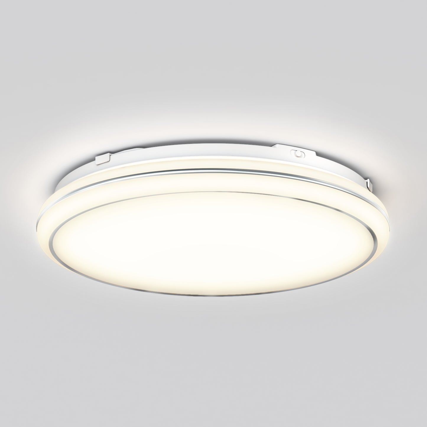The Emina 13 in. LED flush mount light by Artika, featuring 3 CCT options, is a modern round white fixture that emits a soft, bright glow and is shown mounted on a plain light gray ceiling.