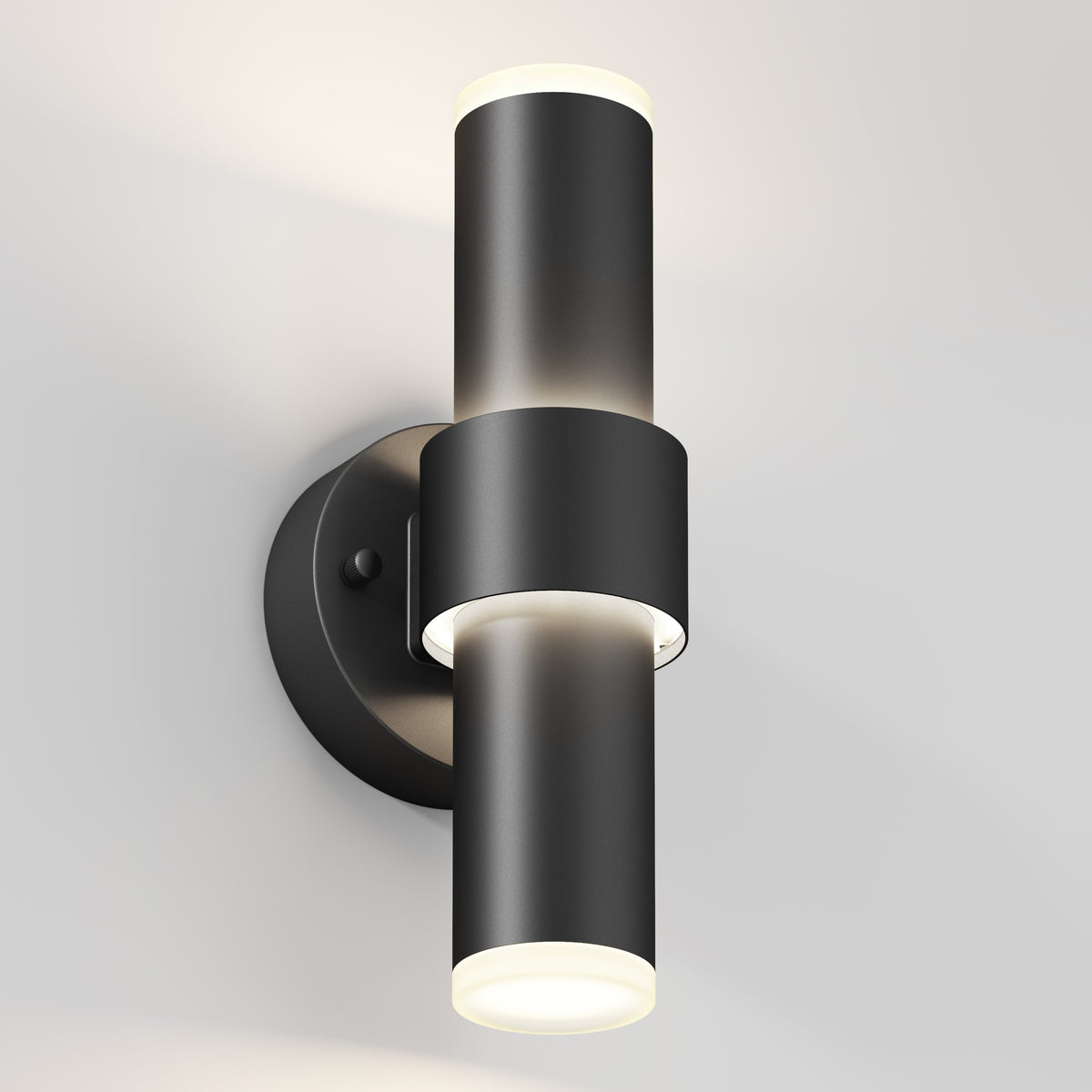 The Artika Dani modern LED indoor-outdoor wall light 5 CCT is a sleek black cylindrical sconce with up-and-down lights on a round base, shown mounted on a light-colored wall.