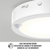 Close-up of a round white ceiling light with a built-in light and motion sensor. Text below in English, French, and Spanish reads: Light and motion sensor / Détecteur de lumière et de mouvement / Sensor de luz y de movimiento.