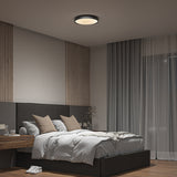 A modern bedroom with a large bed, gray bedding, beige pillows, a wooden nightstand, floor-to-ceiling curtains, a potted plant, and a round ceiling light. The room has a minimalist, neutral-toned design.