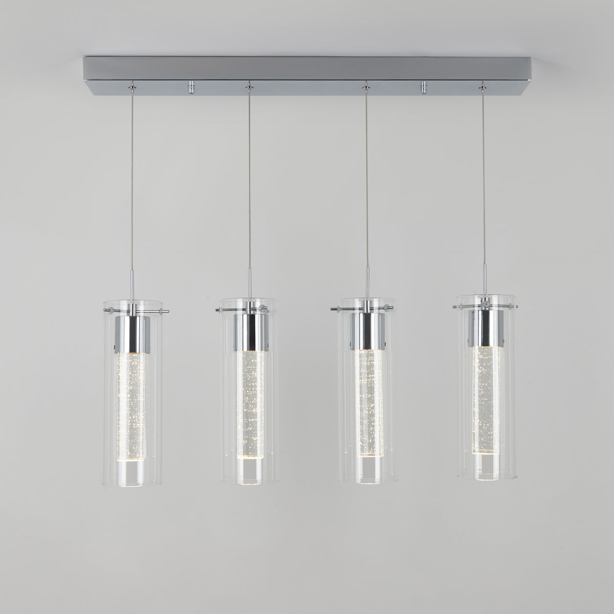 The Artika Essence 4-light LED pendant features four cylindrical glass shades suspended by thin wires with chrome accents, shown against a plain light gray background.
