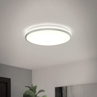 The Artika Macy 15 in. LED RGB Wifi ceiling light brightens a minimal white room with a green leafy plant below.