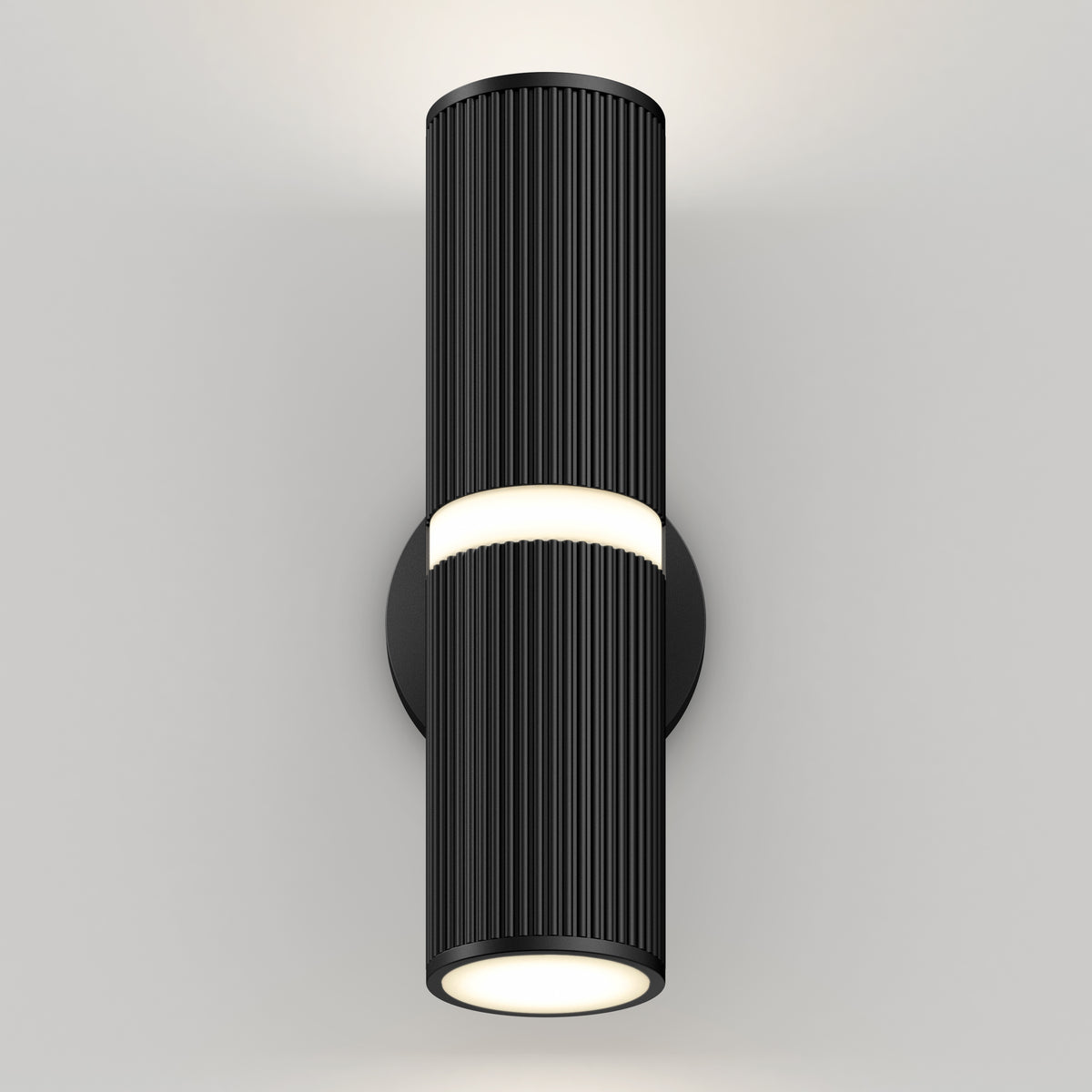 The Groove LED indoor-outdoor wall light by Artika features a modern black cylindrical design with vertical ridges and a round base, casting light from both ends to create a soft glow on any plain white wall.