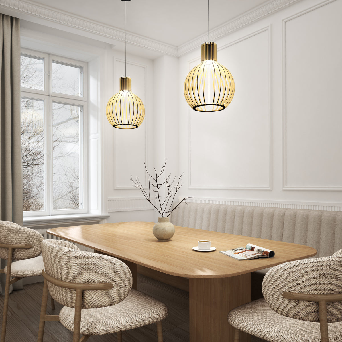 A modern dining room with a wooden table, beige cushioned chairs, a minimalist vase with bare branches, large windows with curtains, and two pendant lights with warm, yellow glow hanging from the ceiling.