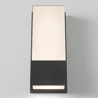 The Artika Dixon indoor-outdoor LED wall light features a modern rectangular design with a black base and frosted glass top, casting a soft warm glow against a plain light gray background.