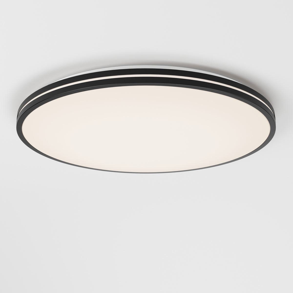 A modern, round ceiling light fixture with a black rim and a smooth white surface, mounted on a plain white ceiling.