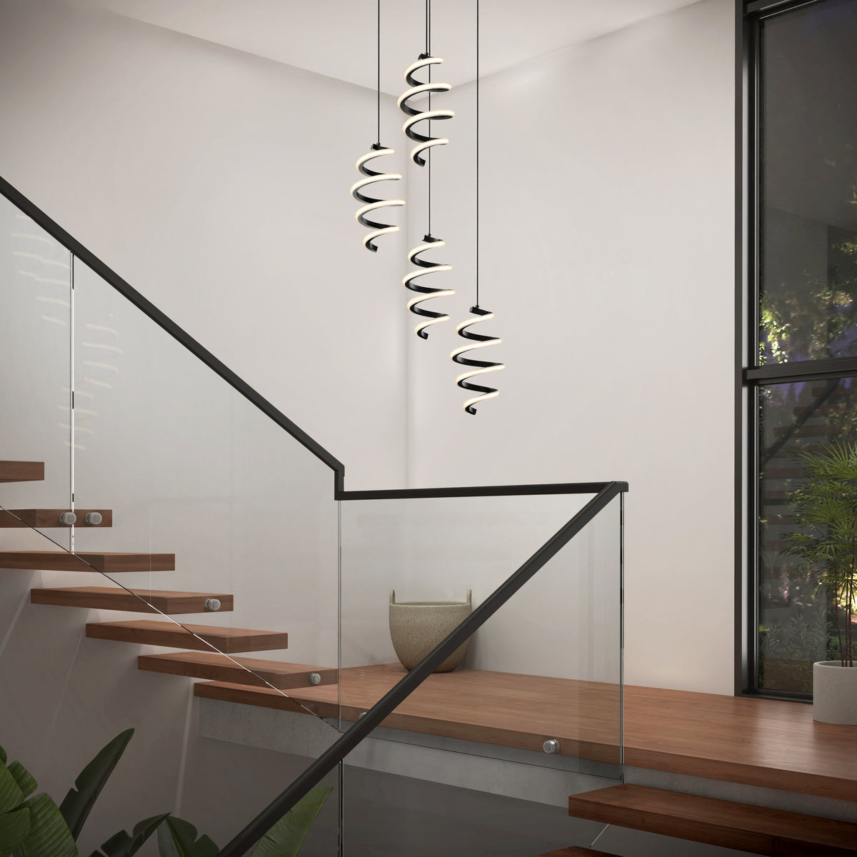 A modern staircase with wooden steps and glass railings features the Artika Chorus 4 light LED pendant 5 CCT. Large windows bring in natural light, and a potted plant decorates the corner.